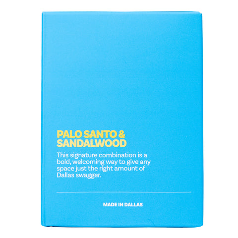 Rear view of blue box with text "PALO SANTO & SANDALWOOD This signature combination is a bold, welcoming way to give any space just the right amount of Dallas swagger. MADE IN DALLAS"